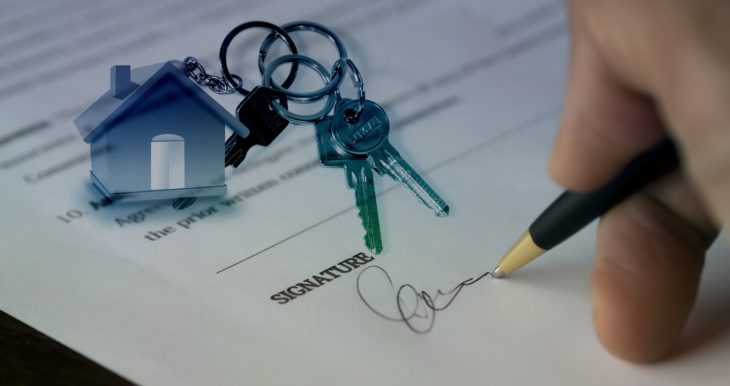 Signature on a contract with a set of house keys next to the contract. 